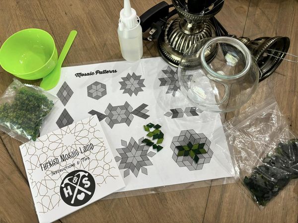 Mosaic-making kit with patterns, materials, and tools on a wooden surface