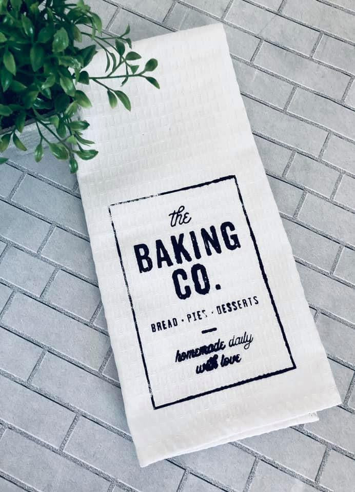 Kitchen towel with 'the Baking Co.' text on a tiled surface