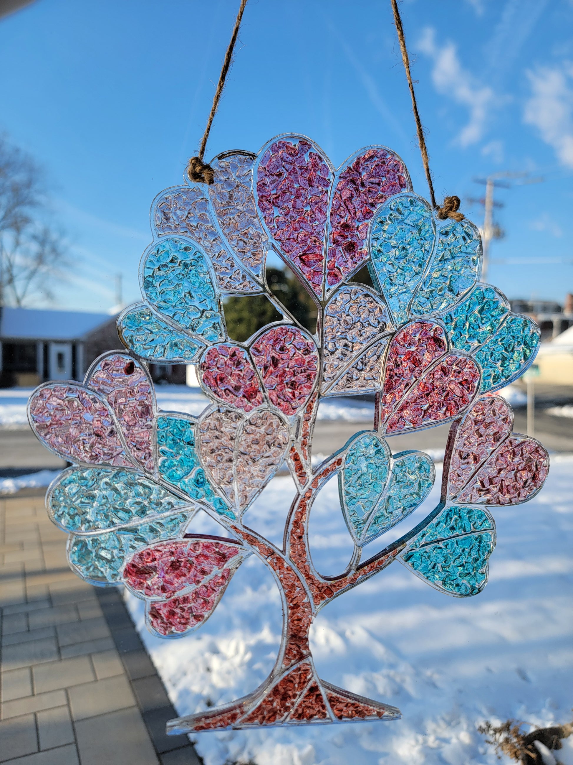 Decorative tree with pink and blue heart-shaped  leaves against a blue sky.
