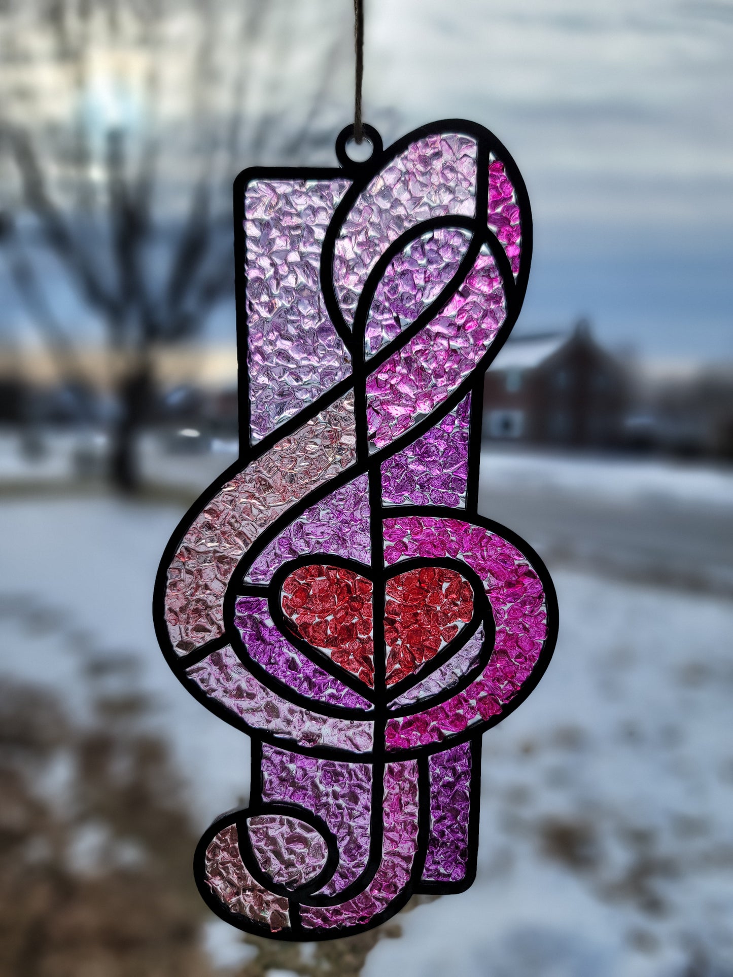 Decorative stained glass music note with pink and purple colors on a blurred background