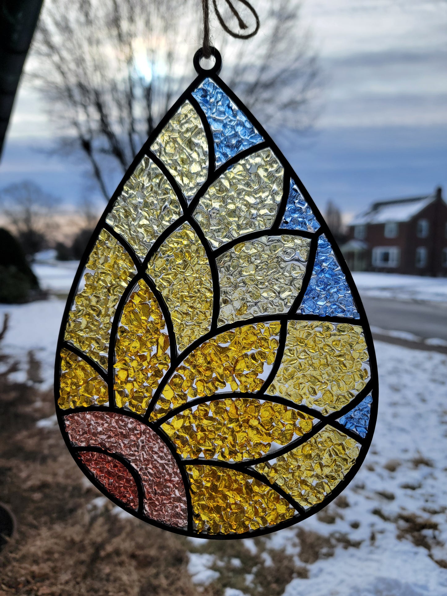Stained glass leaf with multicolored design against a blurred outdoor background