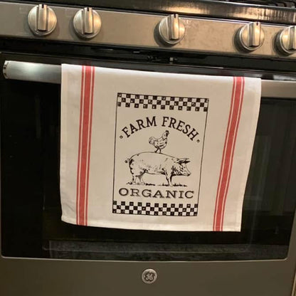 Tea towel with 'Farm Fresh Organic' text and graphics hanging on a stove handle.