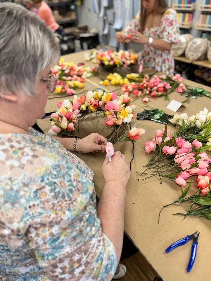People working with flowers at a table in a store setting