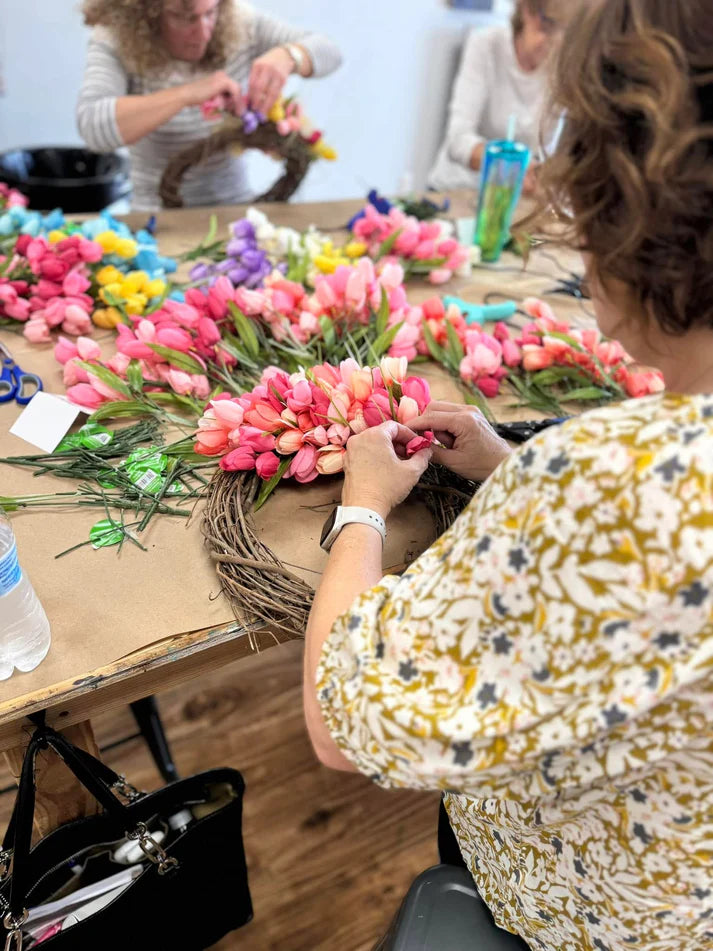 People working on floral arrangements at a table with colorful flowers.