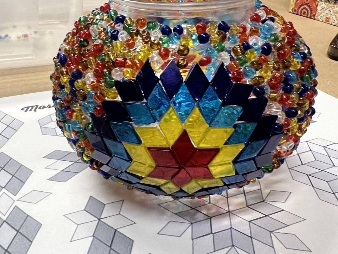 Colorful beaded mosaic ball on a table with geometric patterns