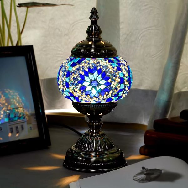 Decorative mosaic table lamp with blue and silver design on a surface.