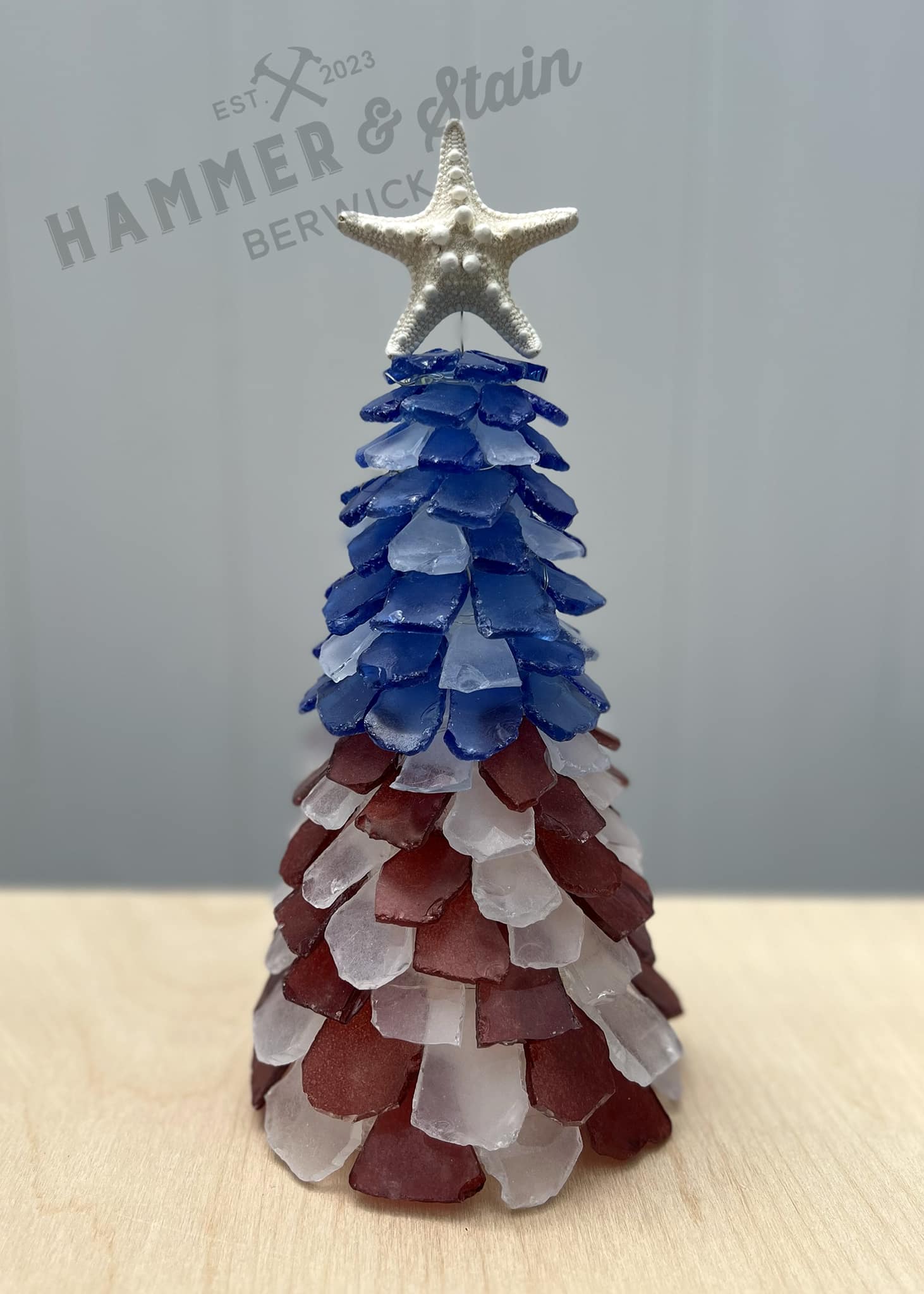 Decorative Christmas tree made of sea glass with a starfish on top, branded 'Hammer & Stain'.