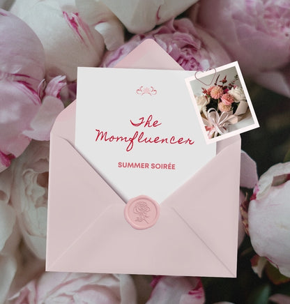 Pink envelope with 'The Momfluencer' invitation on pink flowers