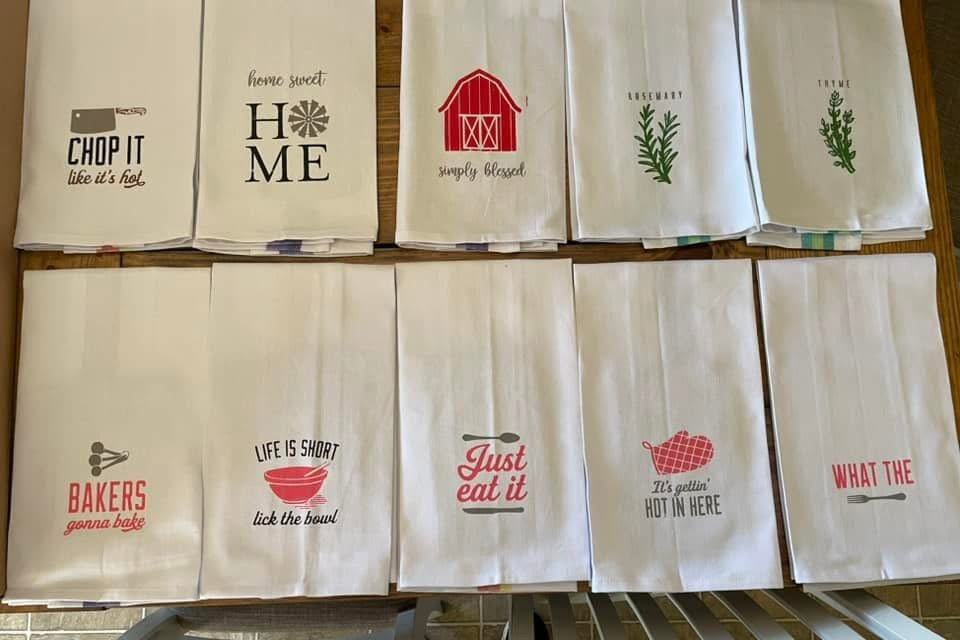 Set of decorative kitchen towels with various prints on a wooden rack.