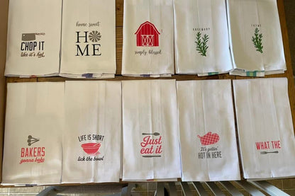 Set of decorative kitchen towels with various prints on a wooden rack.