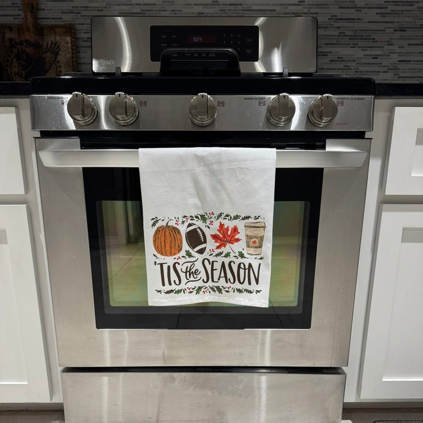 Stainless steel oven with a decorative towel on the door handle in a kitchen setting.