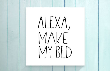 White paper with 'ALEXA, MAKE MY BED' text on a light blue wooden background