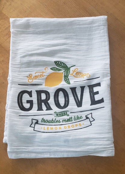 Stack of white towels with 'Sweet Lemon Grove' design on a wooden surface