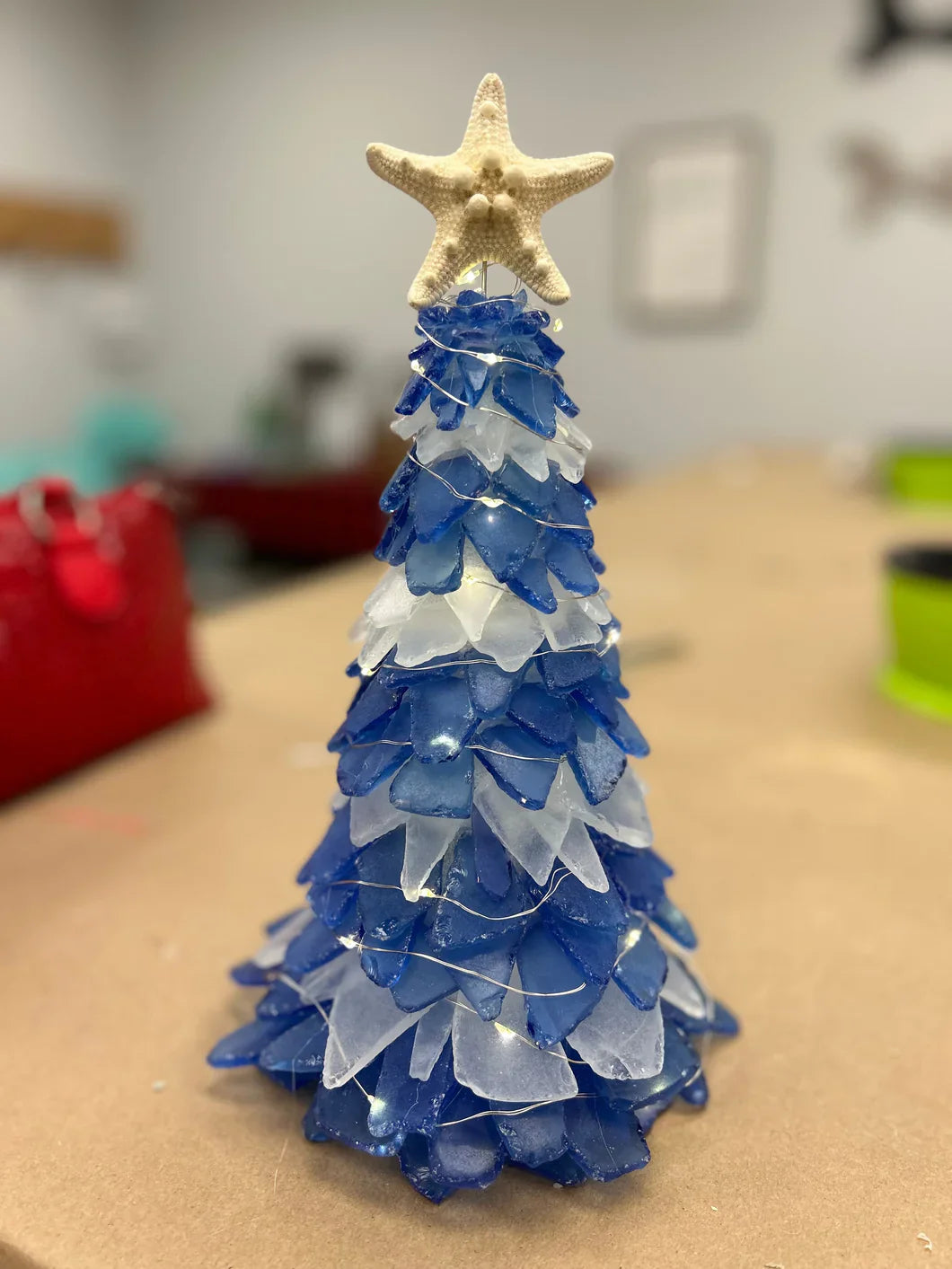 Blue and white decorative Christmas tree with a starfish on top, placed on a table.
