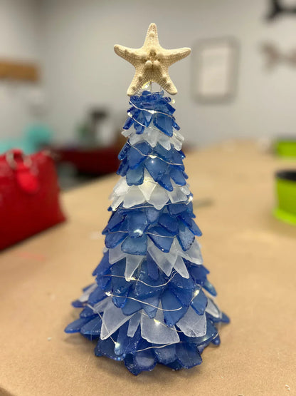 Blue and white decorative Christmas tree with a starfish on top, placed on a table.