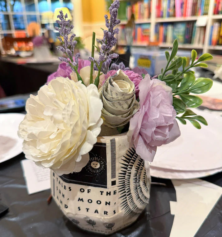 Floral arrangement in a decorative vase on a table with books in the background