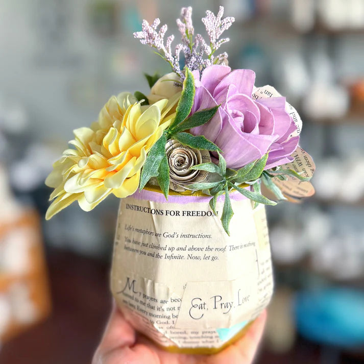 Floral arrangement in a decorative bottle with text on a blurred background