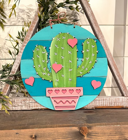 Decorative wall art with a cactus design on a wooden frame.