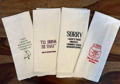 Set of four folded towels with humorous text designs on a wooden surface