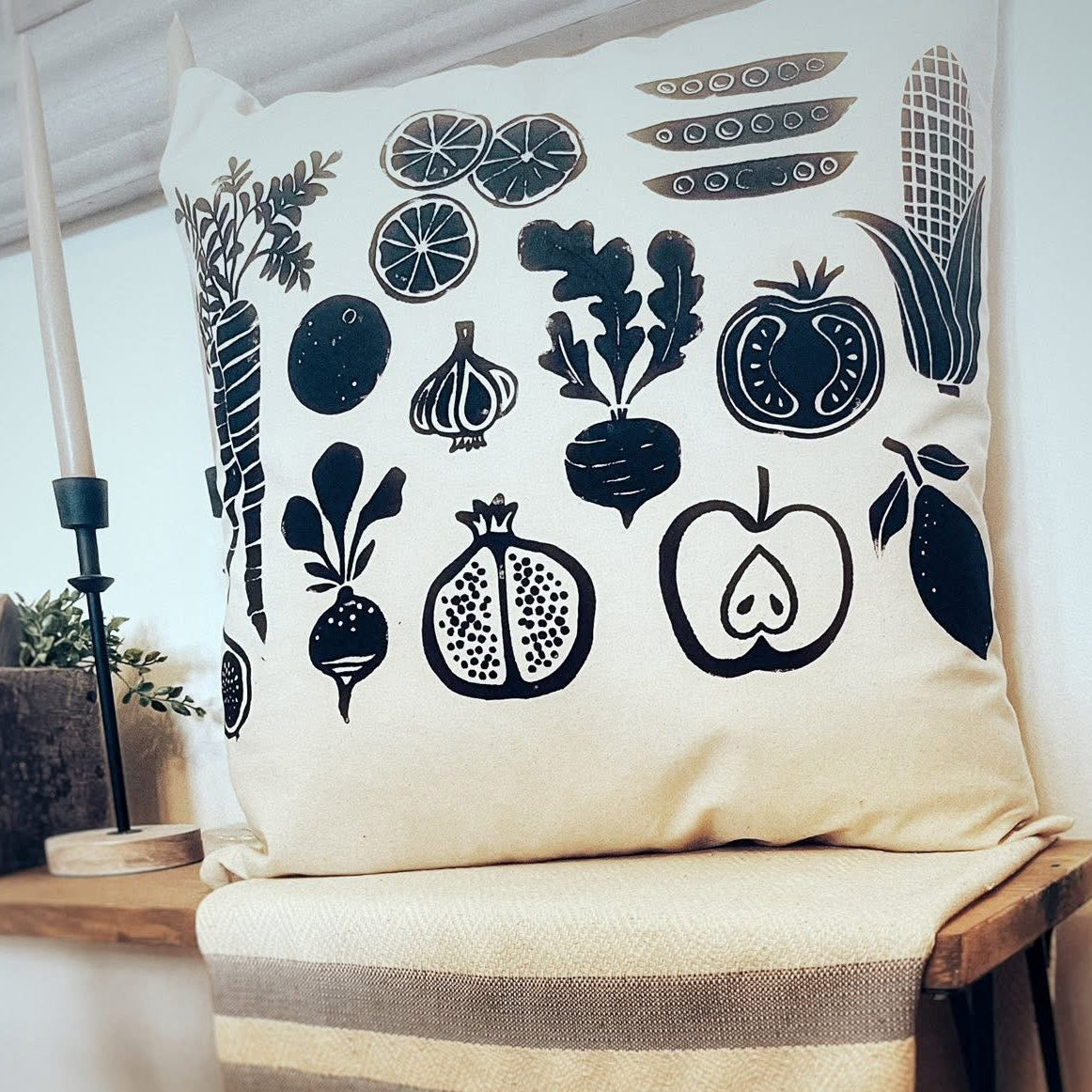 Decorative pillow with black food patterns on a wooden stool in a home setting