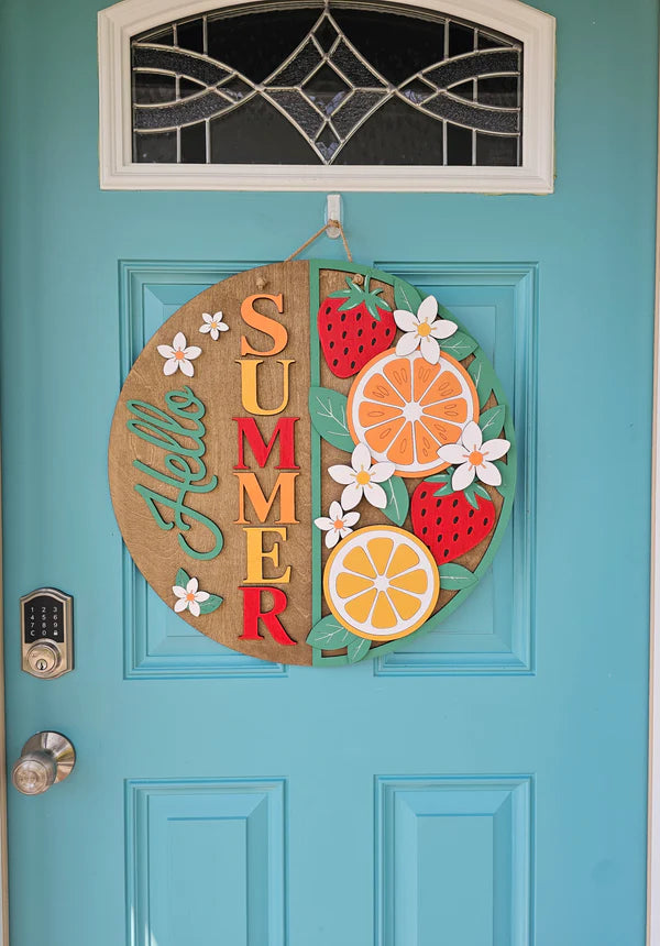 Decorative summer door hanger with fruits and flowers on a turquoise door.