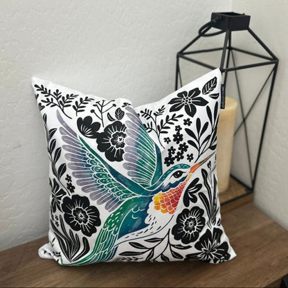 Decorative pillow with a colorful Hummingbird design on a wooden surface.