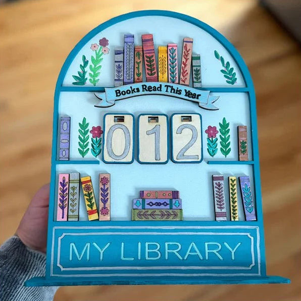 Decorative bookshelf with 'Books Read This Year' and 'My Library' text on a wooden surface.