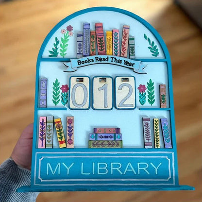 Decorative bookshelf with 'Books Read This Year' and 'My Library' text on a wooden surface.