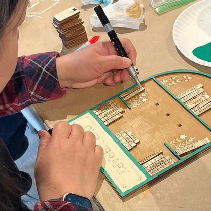 Person using a tool to work on a wooden stamp set on a table.