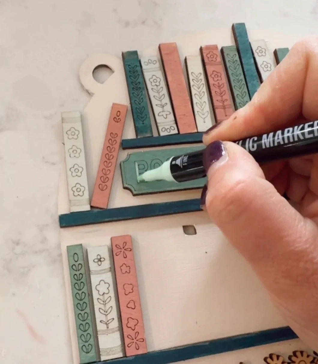 Hand holding a black marker over a set of colorful stamps on a white surface