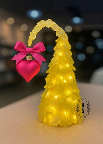 Yellow Cindy Lou Who sea glass tree with a pink heart and bow on a blurred background