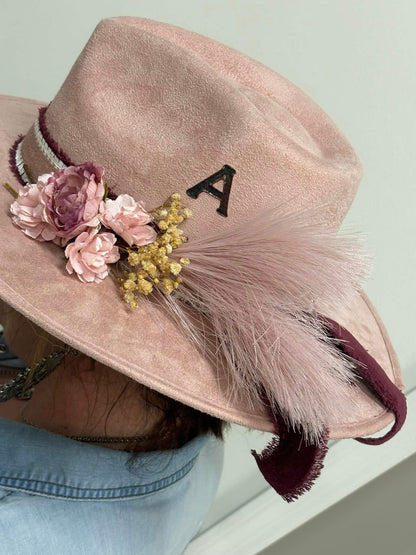 Pink hat with floral decorations and a letter 'A' on a light background