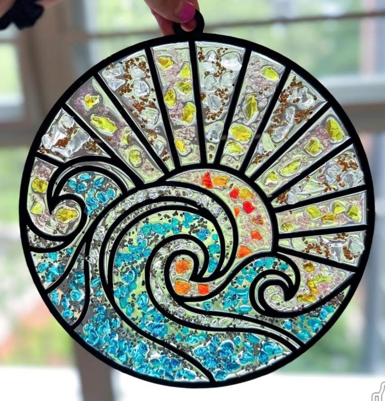 Decorative stained glass wave with a spiral design held by a hand.
