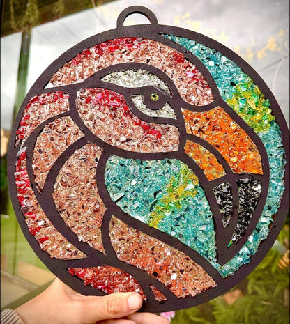Colorful mosaic flamingo design held by a hand with a blurred natural background