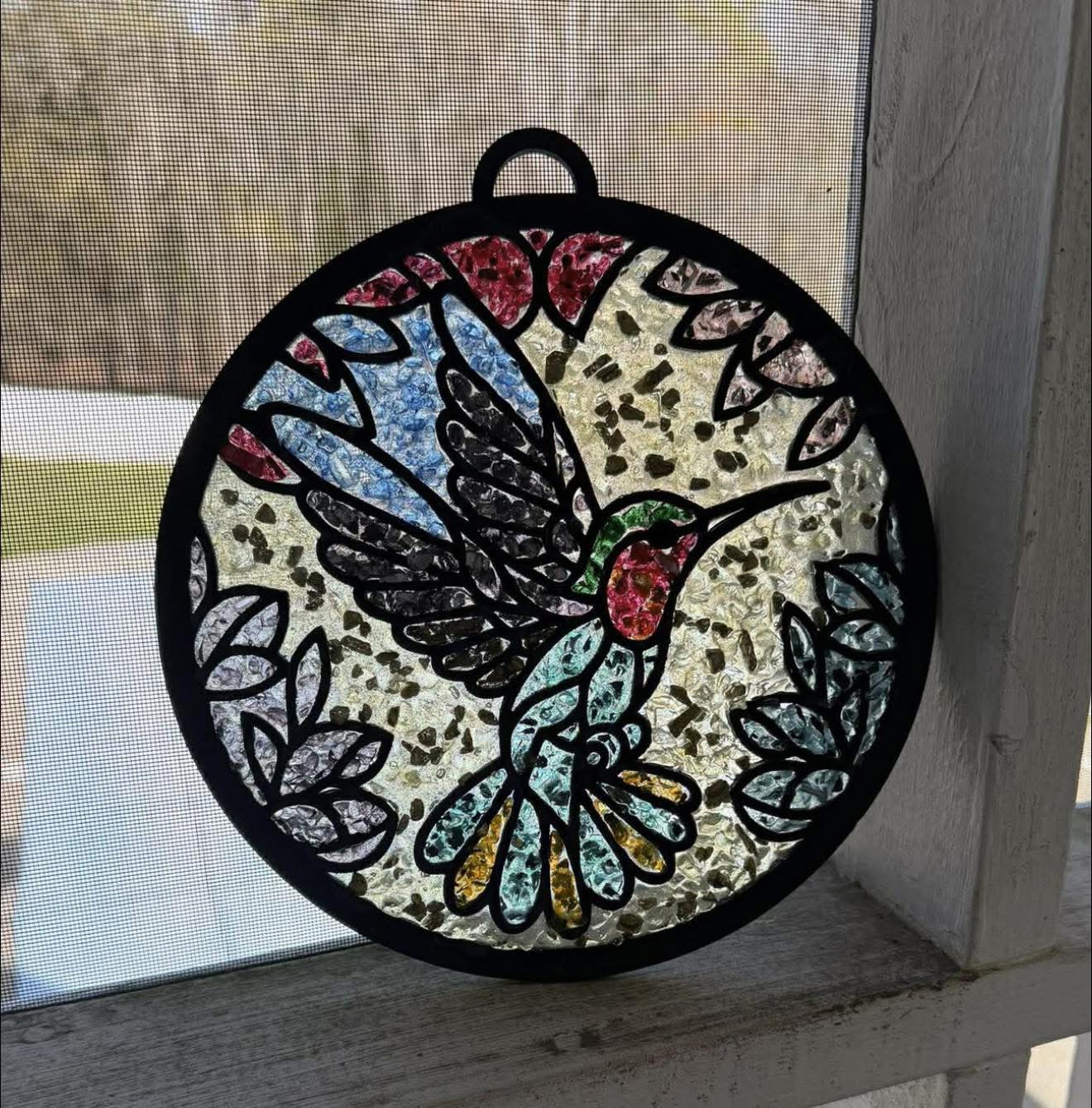 Decorative stained glass hummingbird hanging on a window