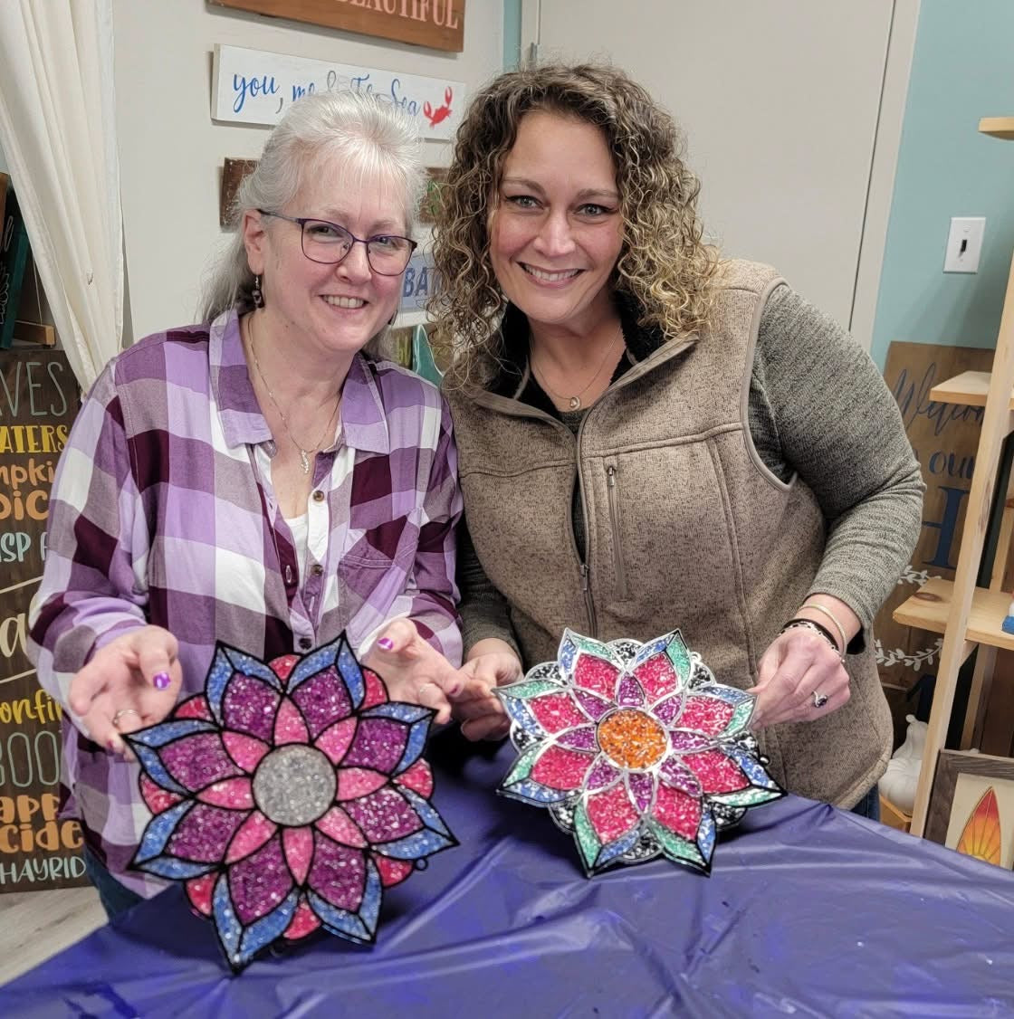 Two women holding colorful flower-shaped objects in a casual indoor setting