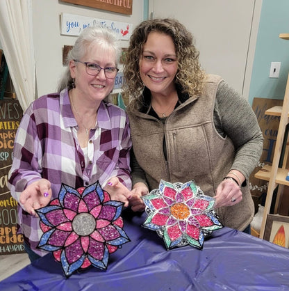 Two women holding colorful flower-shaped objects in a casual indoor setting