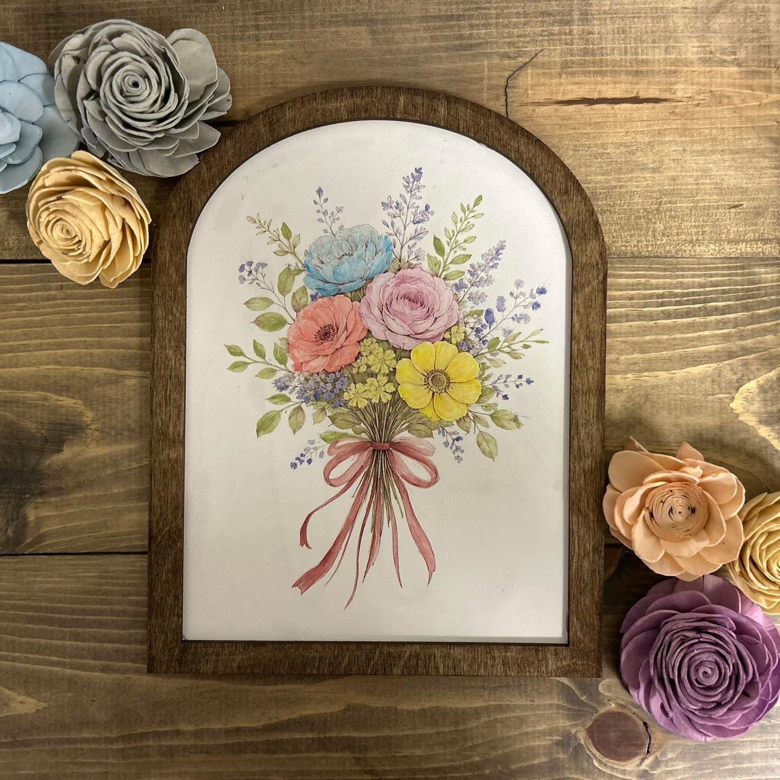 Framed artwork of a floral bouquet with decorative flowers on a wooden surface