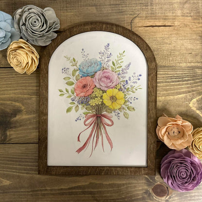 Framed artwork of a floral bouquet with decorative flowers on a wooden surface
