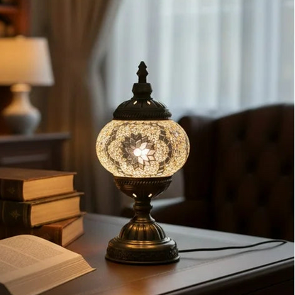 Decorative lamp on a table with books and glasses in a cozy room setting.