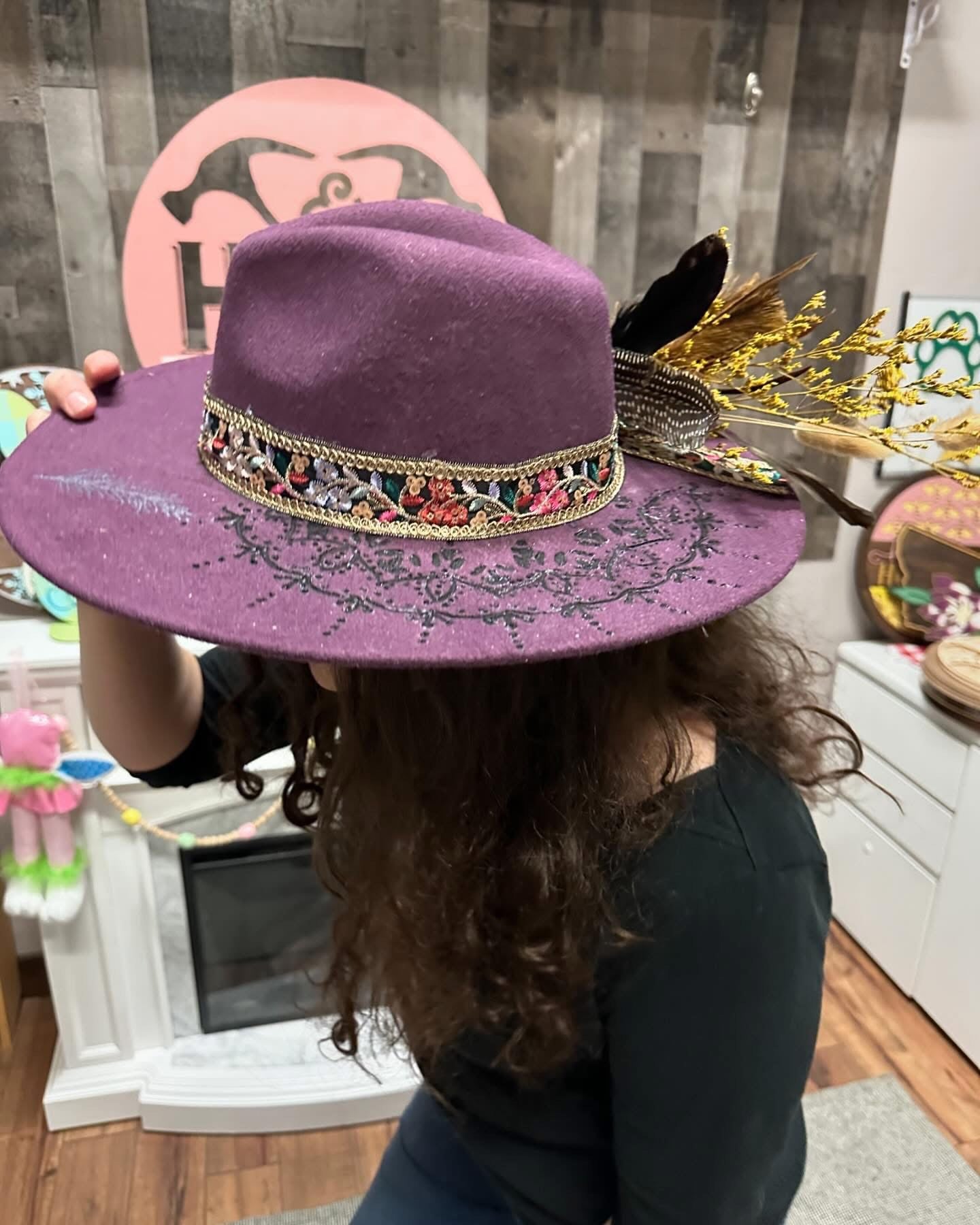 Person wearing a purple hat with decorative band indoors