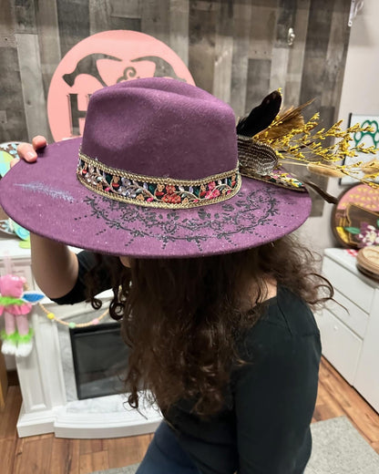 Person wearing a purple hat with decorative band indoors
