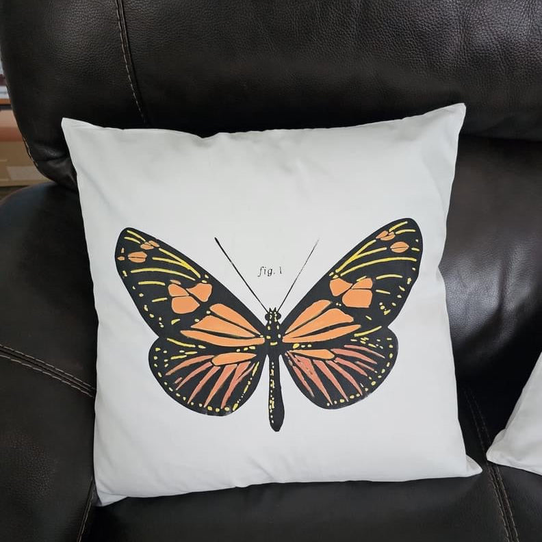 Pillow with butterfly design on a black leather chair