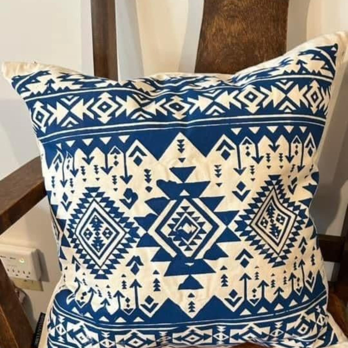 Blue and white patterned pillow on a brown chair