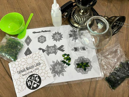 Mosaic-making kit with patterns, materials, and tools on a wooden surface