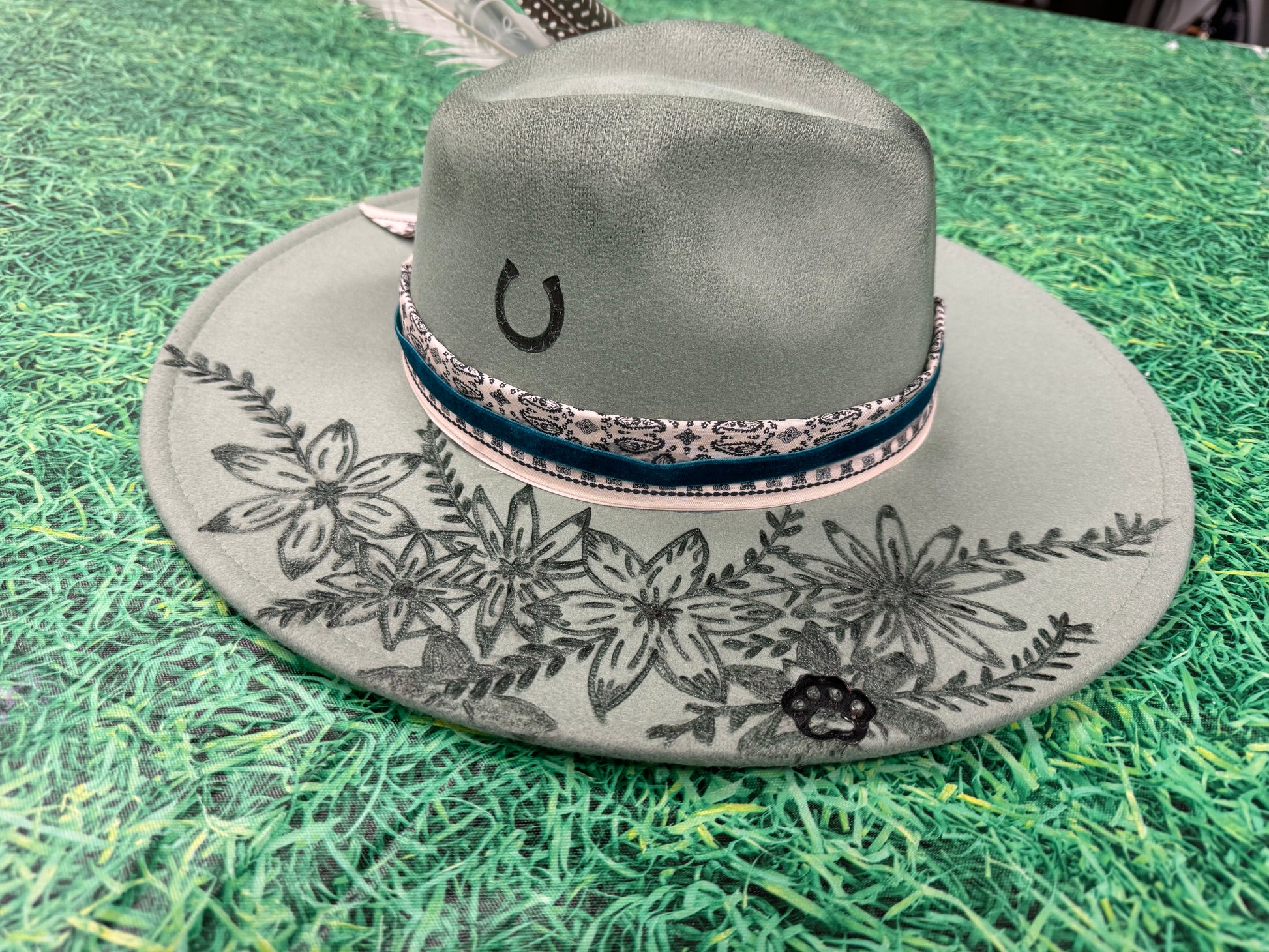 Gray cowboy hat with floral patterns on a green grass-like surface