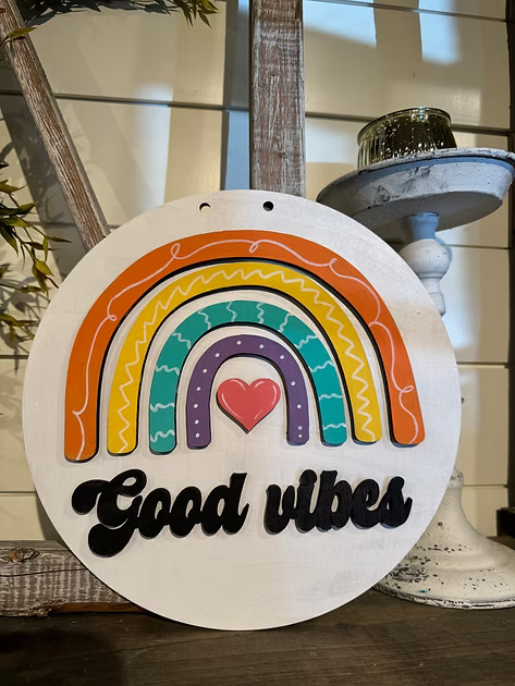 Decorative sign with rainbow and heart design on a white background