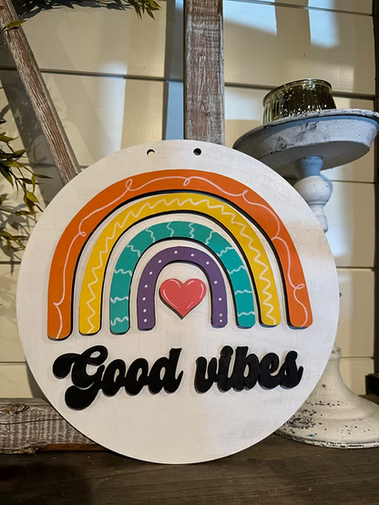 Decorative sign with rainbow and heart design on a white background