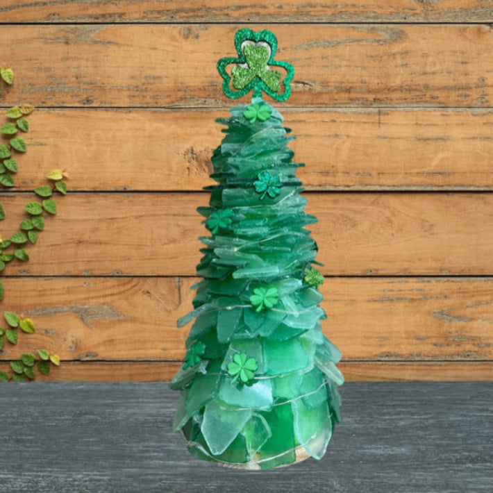 Green sea glass tree with shamrock decorations on a wooden background