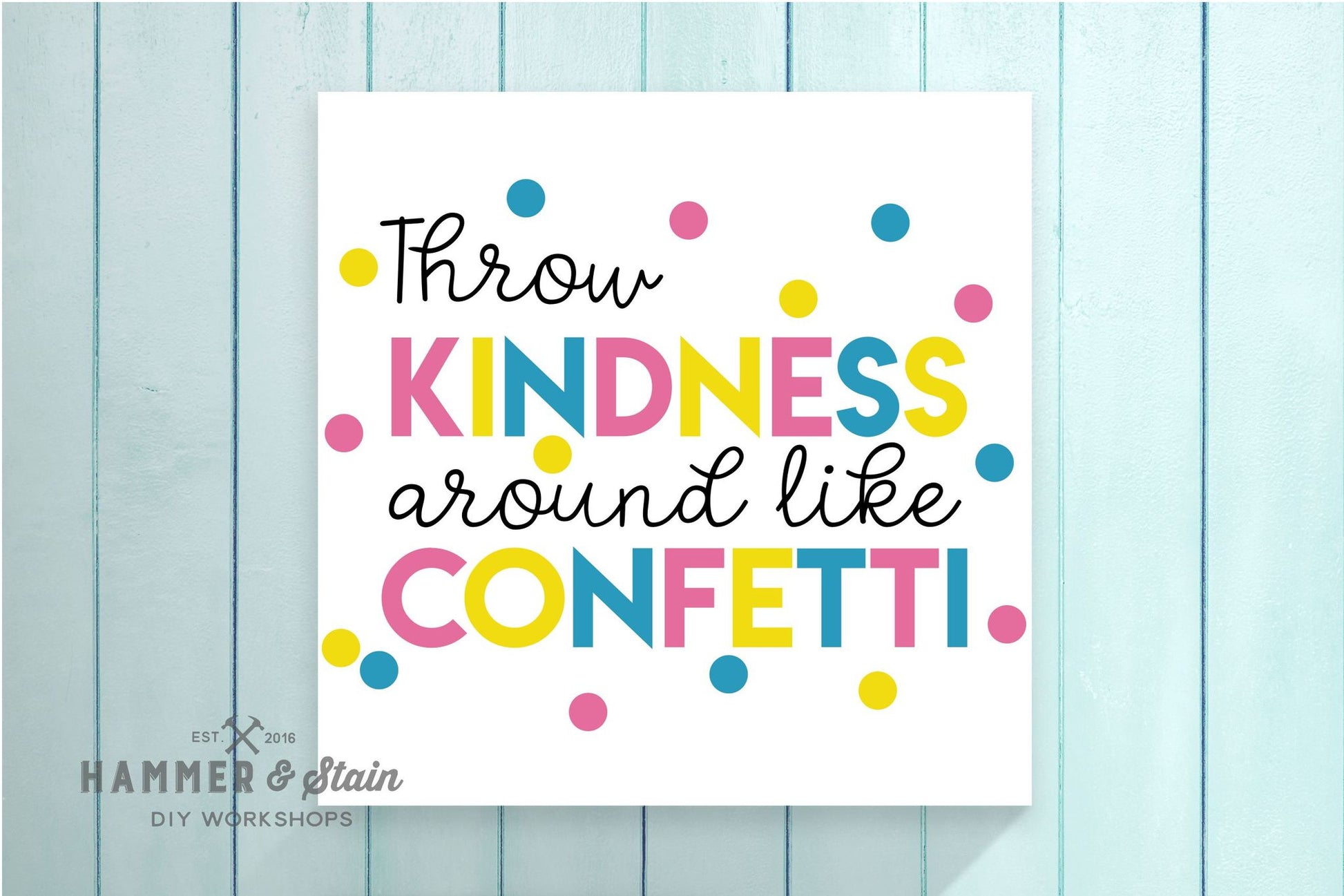 Motivational poster with colorful text 'Throw kindness around like confetti' on a light blue wooden background.